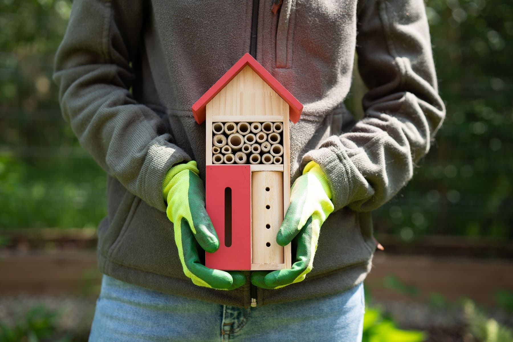 Mains gantées tenant un nichoir à abeilles